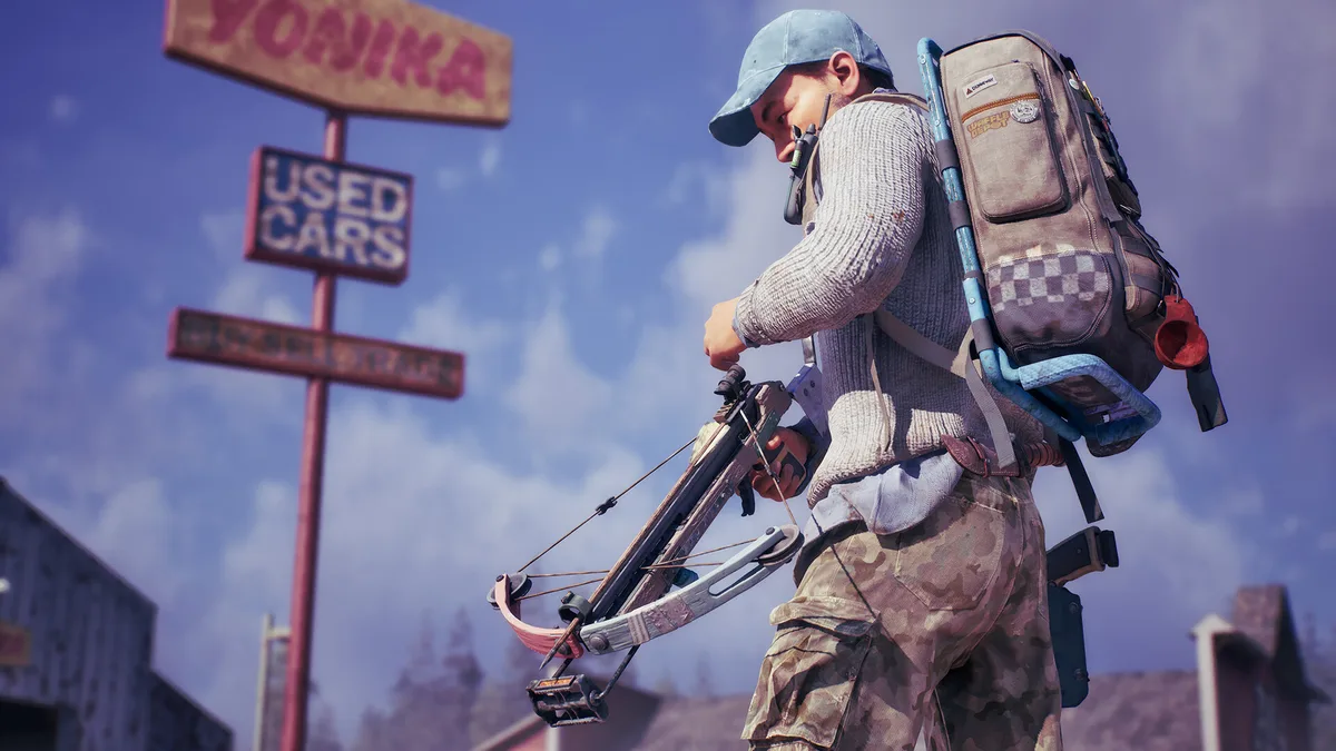 A survivor carrying a crossbow and full scavenging pack past a faded used-cars sign
