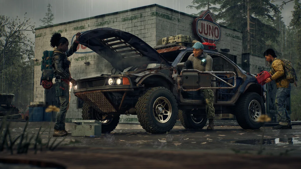 Three survivors working together to repair a vehicle at a rain-soaked gas station